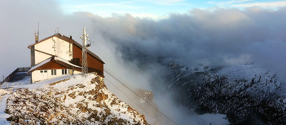 Eine Schutzhütte in Südtirol umgeben von Schnee und Wolken